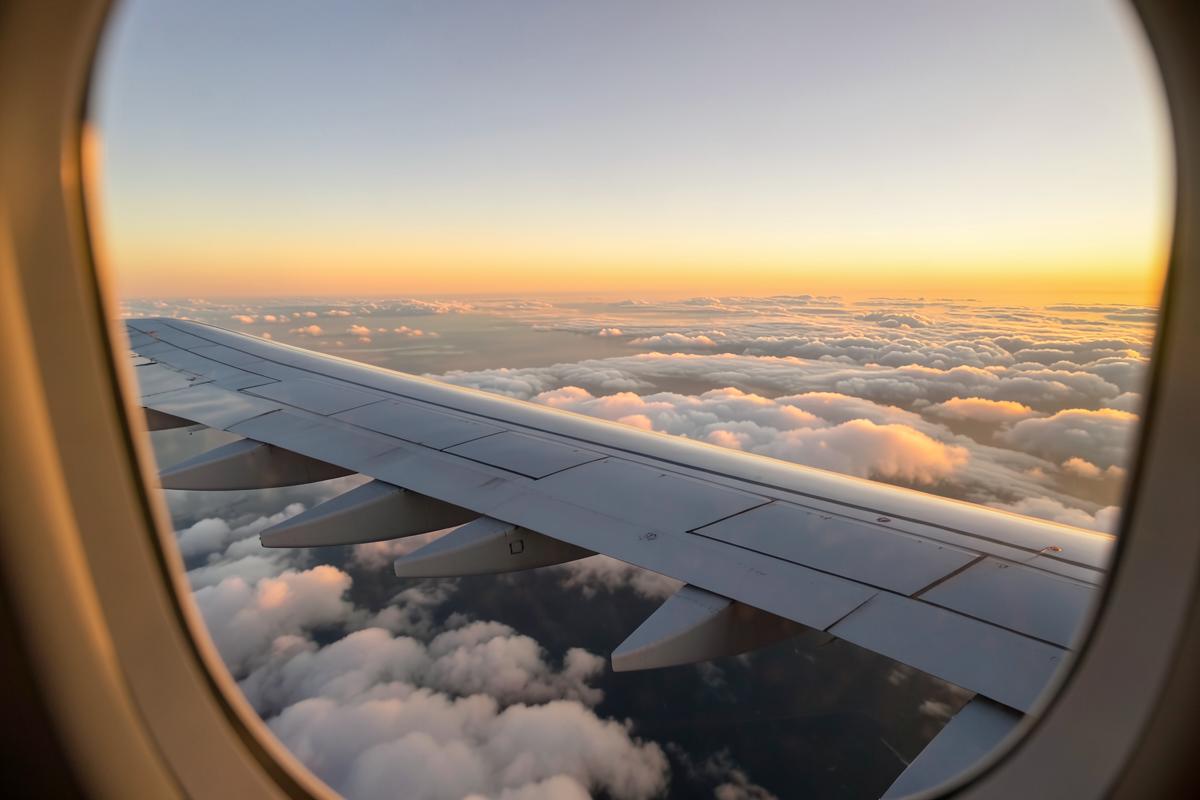 Aile d’un avion de ligne au-dessus des nuages au coucher du soleil